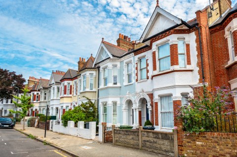 A street of colorful pastel terraced houses under blue sky with puffy white clouds.
