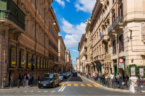 Image of a narrow street lined with tall stone buildings under bright blue sky
