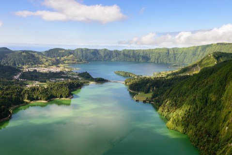 A large turquoise blue lake surrounded by lush green cliffs.