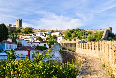 Medieval stone walls bordering village of white buildings with red roofs