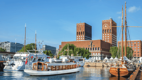 Sailboats in a harbor with brick buildings in the background under clear blue sky